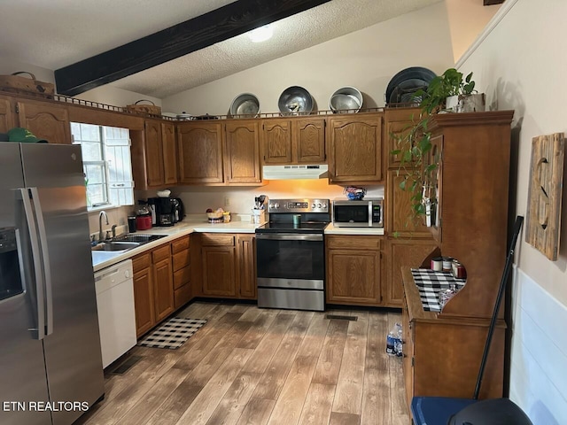 kitchen featuring hardwood / wood-style floors, lofted ceiling with beams, sink, a textured ceiling, and appliances with stainless steel finishes