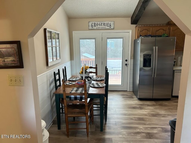 dining room with wood-type flooring, a textured ceiling, and beam ceiling