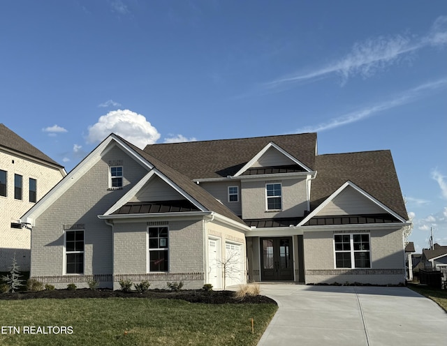 craftsman house featuring a front lawn, a standing seam roof, concrete driveway, metal roof, and brick siding