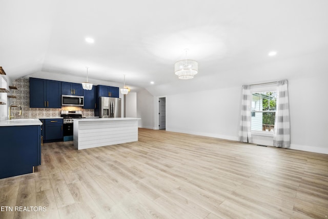 kitchen featuring tasteful backsplash, blue cabinets, a chandelier, vaulted ceiling, and appliances with stainless steel finishes