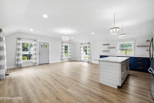 kitchen with a kitchen island, pendant lighting, vaulted ceiling, and a notable chandelier