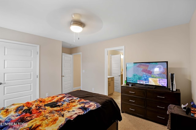 bedroom featuring light carpet, ensuite bath, and a ceiling fan