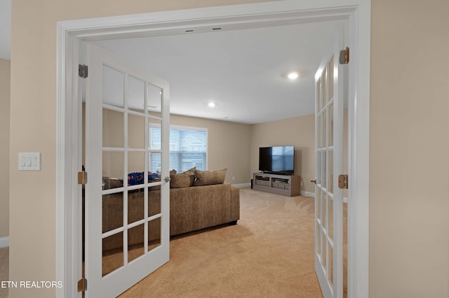 living room with baseboards, french doors, and light colored carpet