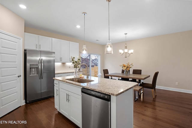 kitchen featuring sink, stainless steel appliances, an island with sink, decorative light fixtures, and white cabinets