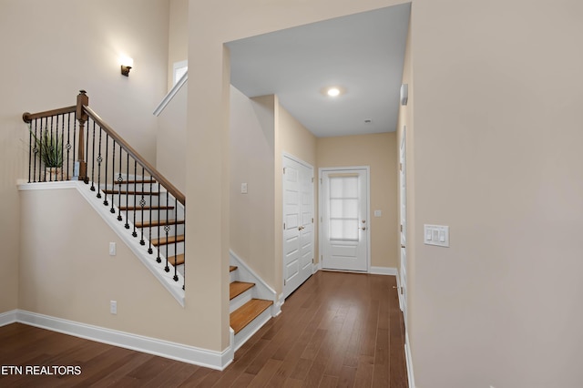 entrance foyer featuring dark wood-style flooring, stairway, and baseboards