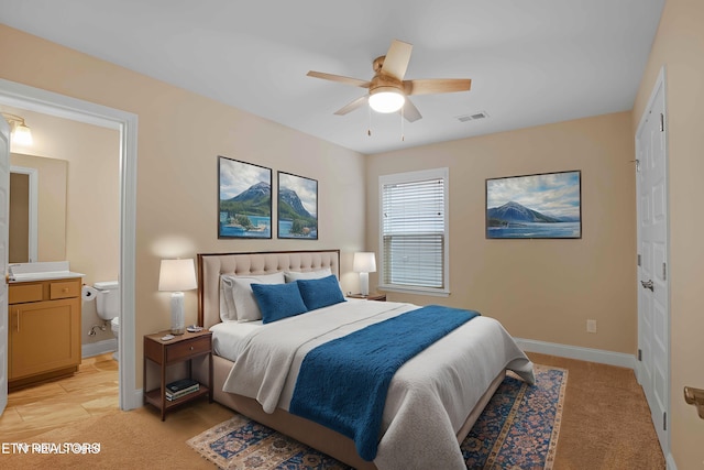 bedroom with light carpet, ensuite bath, baseboards, and visible vents