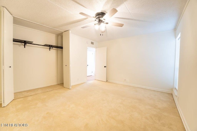 unfurnished bedroom with ceiling fan, light colored carpet, and a textured ceiling