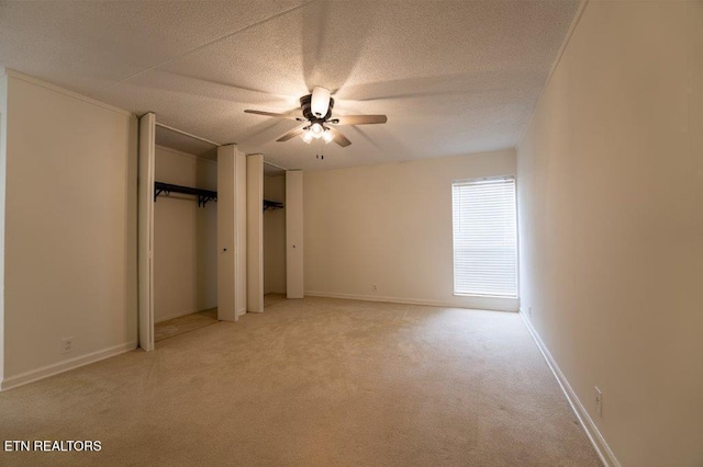 unfurnished bedroom featuring ceiling fan, light colored carpet, and a textured ceiling