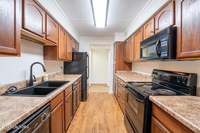 kitchen featuring light hardwood / wood-style floors, black appliances, sink, crown molding, and a textured ceiling