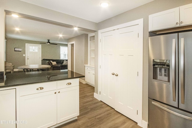 kitchen featuring white cabinets, stainless steel fridge with ice dispenser, ceiling fan, dark stone countertops, and wood-type flooring