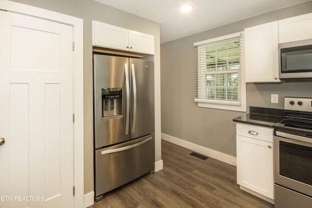 kitchen with white cabinets, appliances with stainless steel finishes, and dark wood-type flooring