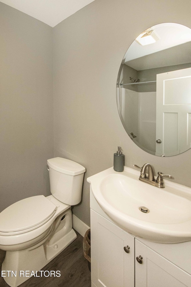 bathroom with a shower, vanity, hardwood / wood-style flooring, and toilet