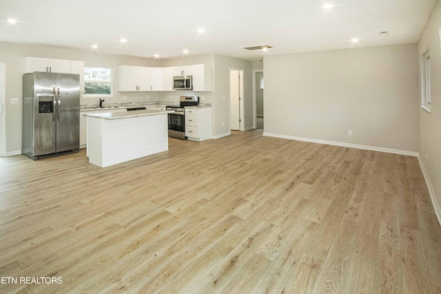 kitchen featuring white cabinetry, light hardwood / wood-style flooring, a kitchen island, and appliances with stainless steel finishes