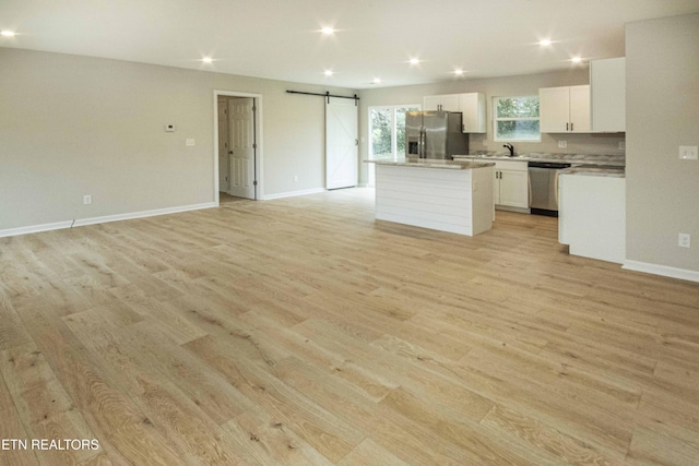 kitchen featuring a barn door, a center island, light wood-type flooring, and appliances with stainless steel finishes