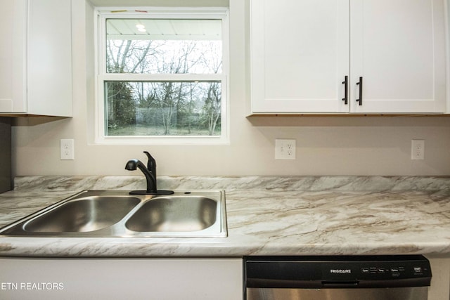 kitchen with stainless steel dishwasher, white cabinetry, and sink