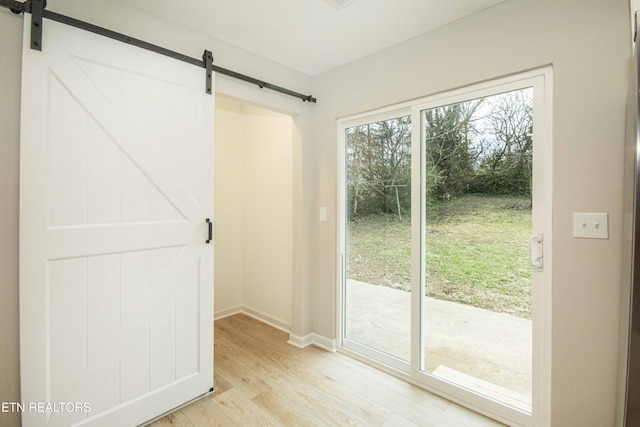 entryway with a barn door and light hardwood / wood-style flooring