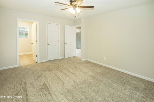 unfurnished bedroom featuring light carpet, connected bathroom, and ceiling fan