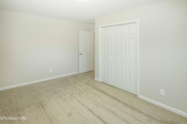 unfurnished bedroom featuring light carpet and a closet