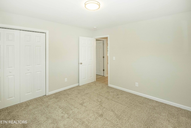 unfurnished bedroom with light colored carpet and a closet