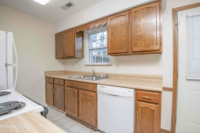 kitchen featuring sink, light tile patterned floors, and white appliances