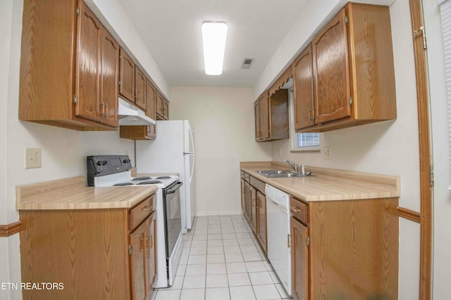 kitchen with a textured ceiling, light tile patterned flooring, white appliances, and sink