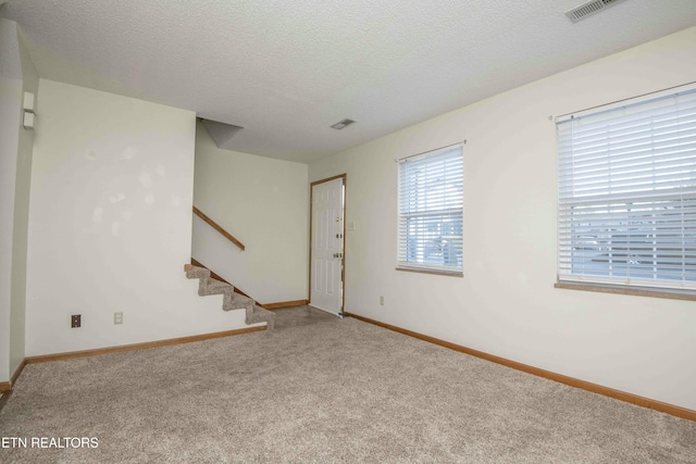 carpeted empty room with a textured ceiling