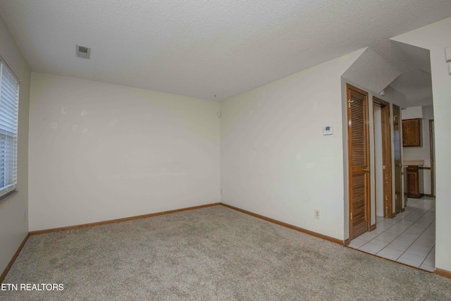 empty room featuring light colored carpet and a textured ceiling