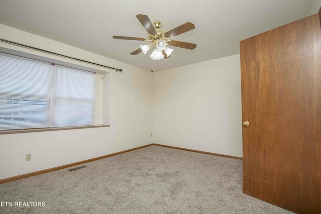 carpeted empty room with ceiling fan and a textured ceiling