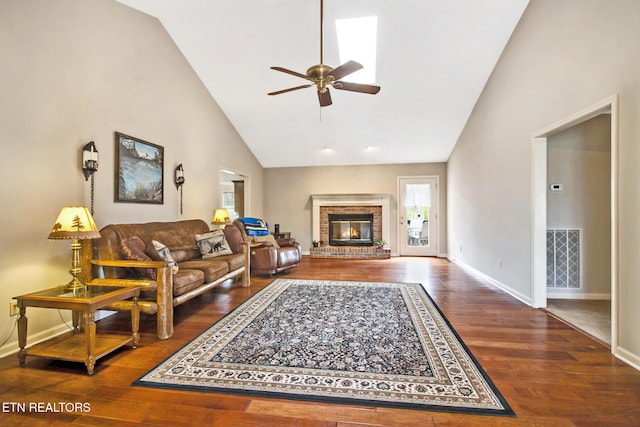 living room featuring ceiling fan, hardwood / wood-style floors, high vaulted ceiling, and a brick fireplace