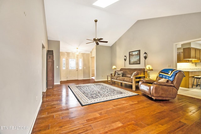 living room with dark hardwood / wood-style flooring, a skylight, high vaulted ceiling, and ceiling fan