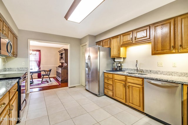 kitchen with light stone countertops, stainless steel appliances, light tile patterned flooring, and sink