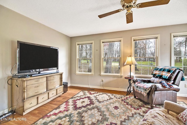 living room featuring ceiling fan, wood-type flooring, a textured ceiling, and vaulted ceiling