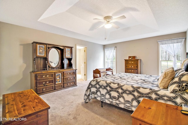 bedroom featuring multiple windows, a textured ceiling, a tray ceiling, and ceiling fan