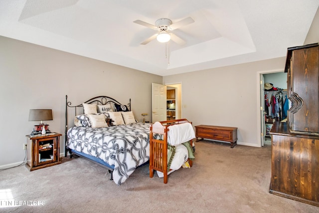 bedroom featuring a closet, a tray ceiling, a spacious closet, and ceiling fan