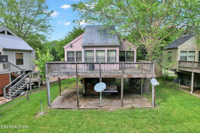 rear view of property featuring a sunroom, a patio area, a deck, and a lawn