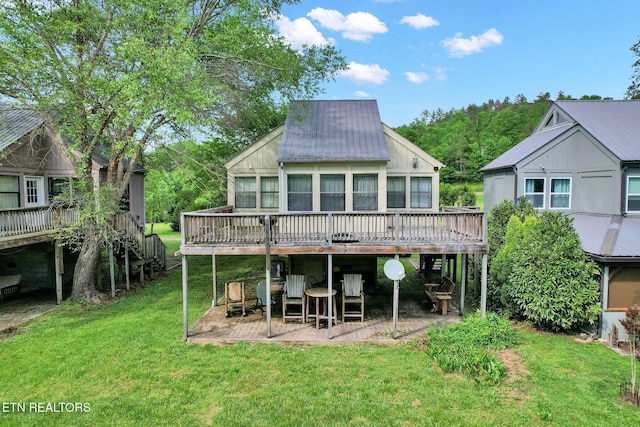 rear view of house with a lawn, a wooden deck, and a patio