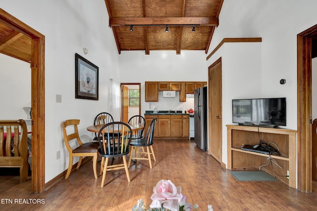 dining space with hardwood / wood-style floors, wooden ceiling, high vaulted ceiling, track lighting, and beam ceiling