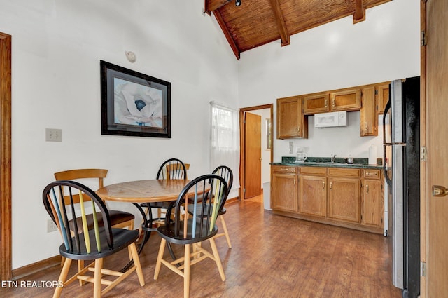 dining area featuring high vaulted ceiling, sink, beamed ceiling, wood-type flooring, and wood ceiling