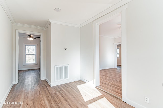 spare room featuring ceiling fan, crown molding, and light wood-type flooring