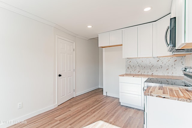 kitchen with wood counters, backsplash, white cabinets, crown molding, and stainless steel appliances