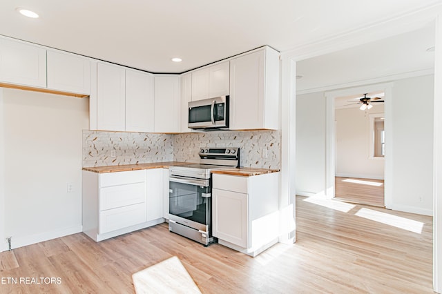 kitchen featuring butcher block countertops, white cabinetry, stainless steel appliances, and light wood-type flooring