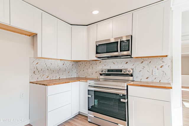 kitchen with light hardwood / wood-style floors, white cabinetry, butcher block counters, and stainless steel appliances