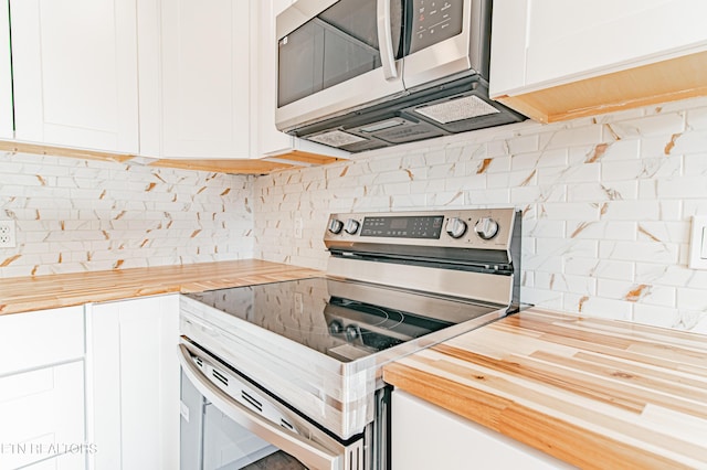 kitchen featuring butcher block countertops, backsplash, white cabinetry, and stainless steel appliances