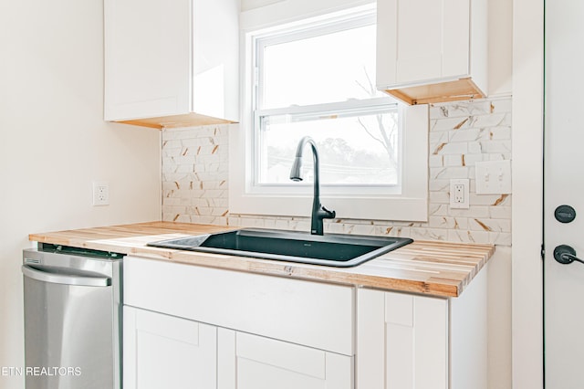 kitchen featuring white cabinets, butcher block countertops, sink, and tasteful backsplash