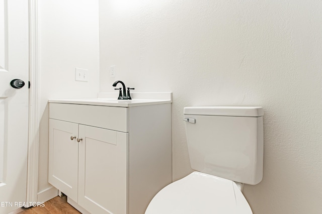 bathroom with toilet, vanity, and hardwood / wood-style flooring