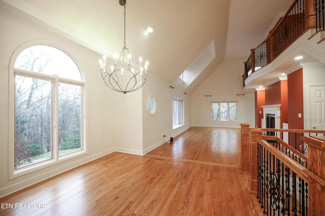 living room with high vaulted ceiling, light hardwood / wood-style flooring, and a notable chandelier