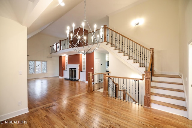 living room with a notable chandelier, hardwood / wood-style flooring, and a high ceiling