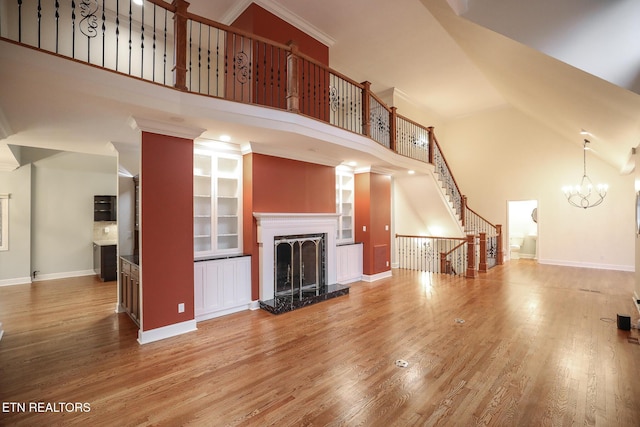 unfurnished living room featuring a towering ceiling, wood-type flooring, and a premium fireplace