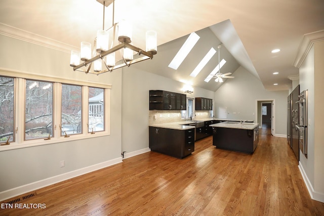 kitchen with pendant lighting, sink, hardwood / wood-style flooring, dark brown cabinets, and a kitchen island