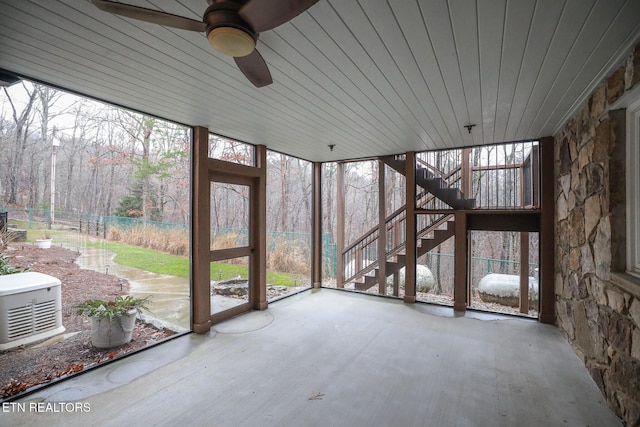 unfurnished sunroom featuring ceiling fan, wooden ceiling, and a healthy amount of sunlight